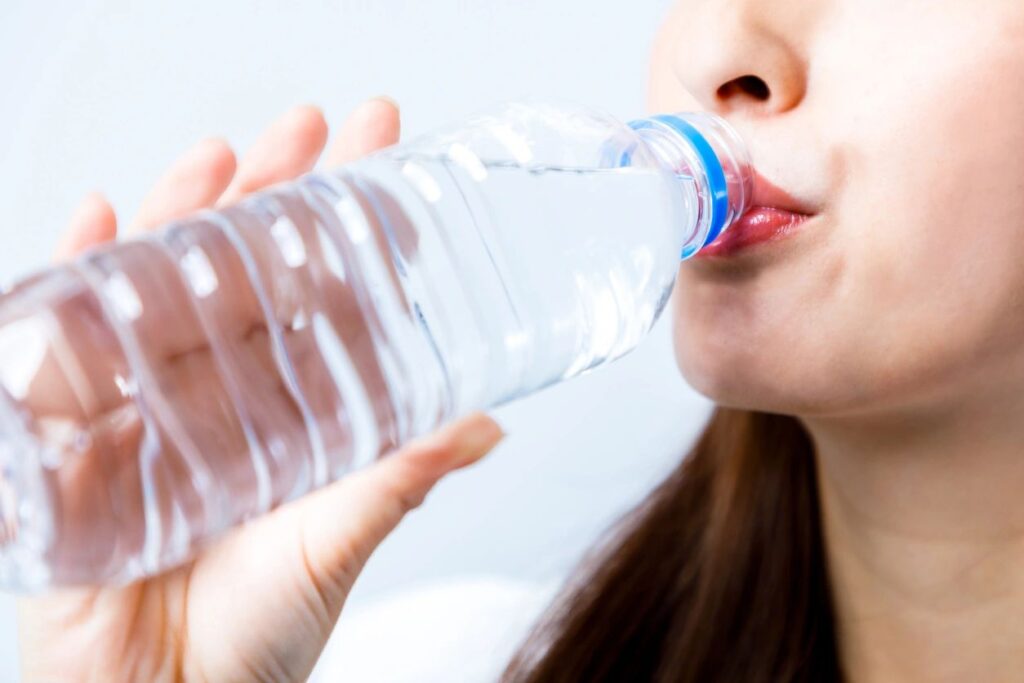 A woman drinking water to optimize her recovery from chiropractic care.