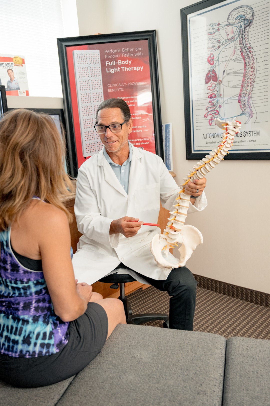 Dr. Brian answering a patient's question holding a spine